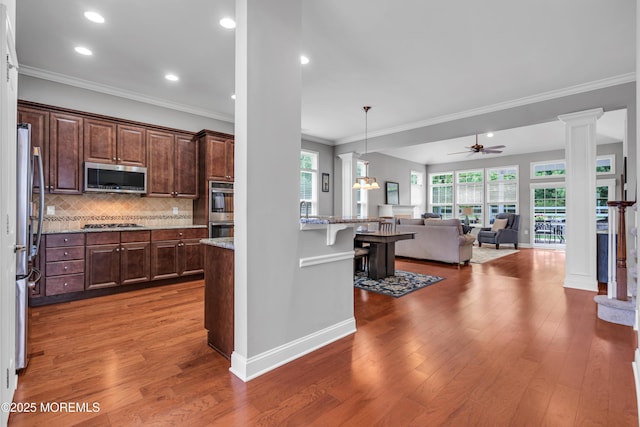 24 Beach Haven Way, Waretown, NJ 08758 - kitchen with stainless steel appliances, ornate columns, a kitchen bar, healthy amount of natural light, and ornamental molding