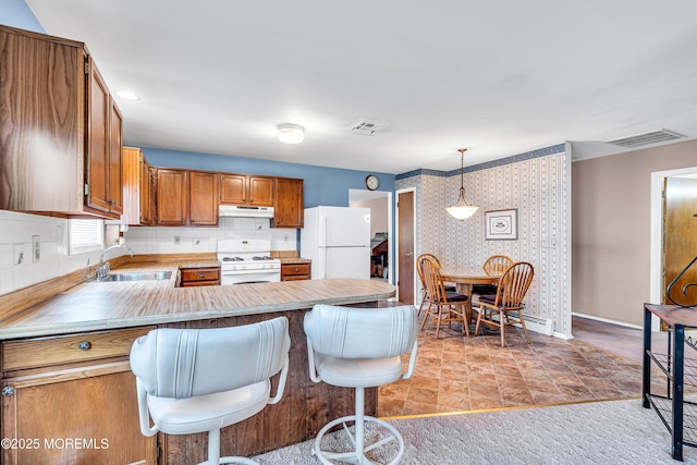 184 Pulaski Blvd, Toms River, NJ 08757 - kitchen with white appliances, a sink, under cabinet range hood, wallpapered walls, and brown cabinetry