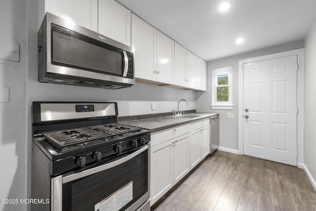317 Bath Ave Unit 2, Long Branch, NJ 07740 - kitchen with stainless steel appliances, a sink, wood finished floors, white cabinets, and baseboards