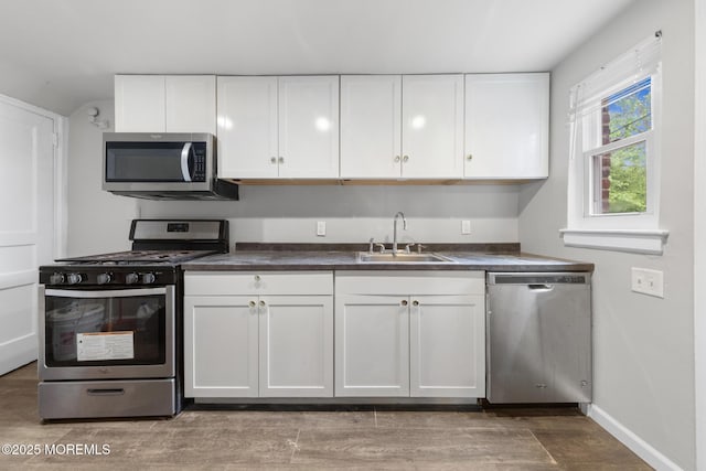 317 Bath Ave Unit 2, Long Branch, NJ 07740 - kitchen featuring stainless steel appliances, a sink, white cabinets, dark countertops, and baseboards
