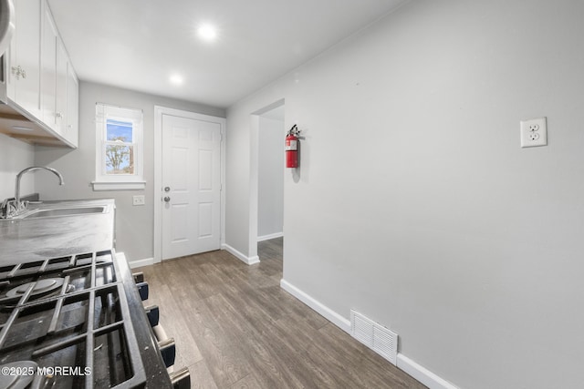 317 Bath Ave Unit 2, Long Branch, NJ 07740 - kitchen with a sink, baseboards, white cabinetry, wood finished floors, and black gas stove