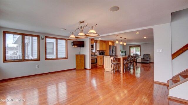 308 16th Ave, Belmar, NJ 07719 - kitchen with stainless steel appliances, open floor plan, a kitchen breakfast bar, a chandelier, and light wood-style floors