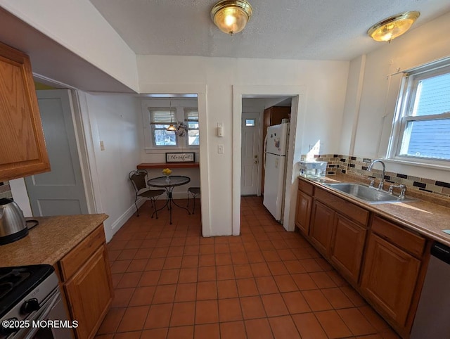 619 Leland Ave, Plainfield, NJ 07062 - kitchen with stainless steel appliances, a sink, light tile patterned floors, decorative backsplash, and brown cabinets