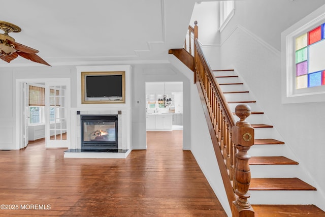 208 Cedar St, Lakehurst, NJ 08733 - staircase featuring plenty of natural light, a glass covered fireplace, hardwood / wood-style floors, a ceiling fan, and crown molding