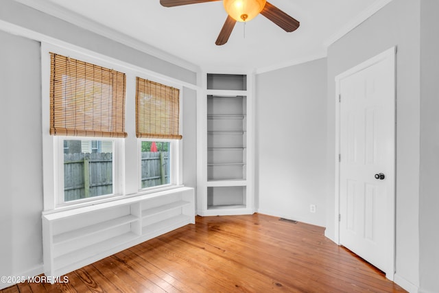 208 Cedar St, Lakehurst, NJ 08733 - empty room featuring built in shelves, wood-type flooring, ornamental molding, and ceiling fan