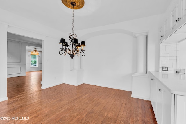 208 Cedar St, Lakehurst, NJ 08733 - unfurnished dining area featuring hardwood / wood-style flooring, ornate columns, a chandelier, and baseboards