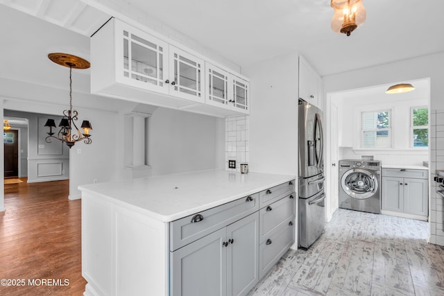 208 Cedar St, Lakehurst, NJ 08733 - kitchen with washer / clothes dryer, stainless steel refrigerator with ice dispenser, light wood-style flooring, glass insert cabinets, and a chandelier