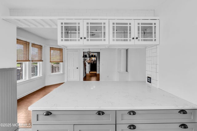 208 Cedar St, Lakehurst, NJ 08733 - kitchen with light stone counters, glass insert cabinets, wood finished floors, gray cabinetry, and a peninsula