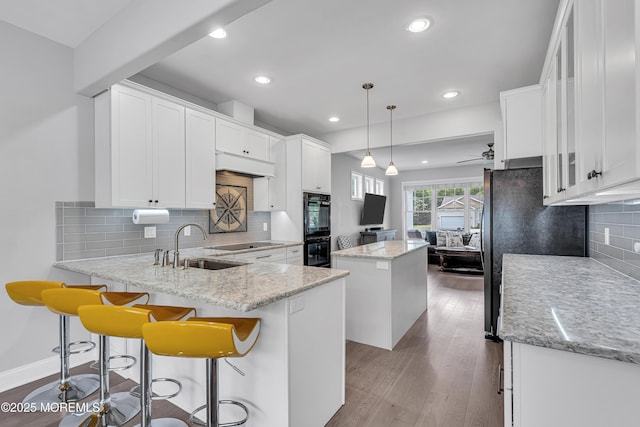 24 Woodview Ln, Cape May Court House, NJ 08210 - kitchen featuring a center island, black appliances, a peninsula, white cabinetry, and tasteful backsplash