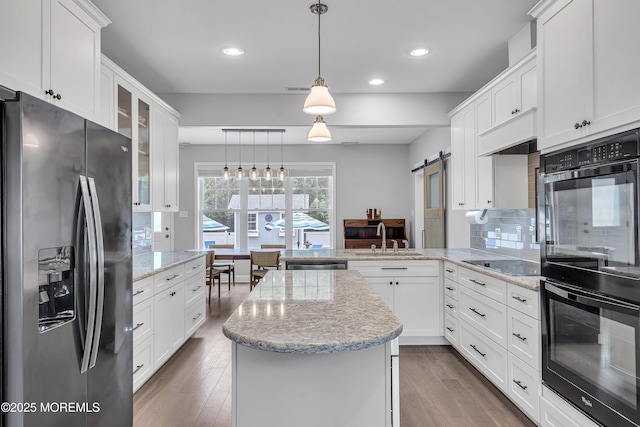 24 Woodview Ln, Cape May Court House, NJ 08210 - kitchen with black appliances, a sink, a peninsula, a barn door, and dark wood-style flooring