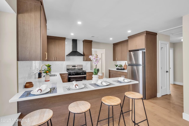 28 Twyford Ln, Manchester, NJ 08759 - kitchen with wall chimney range hood, appliances with stainless steel finishes, a sink, a peninsula, and light wood-style flooring