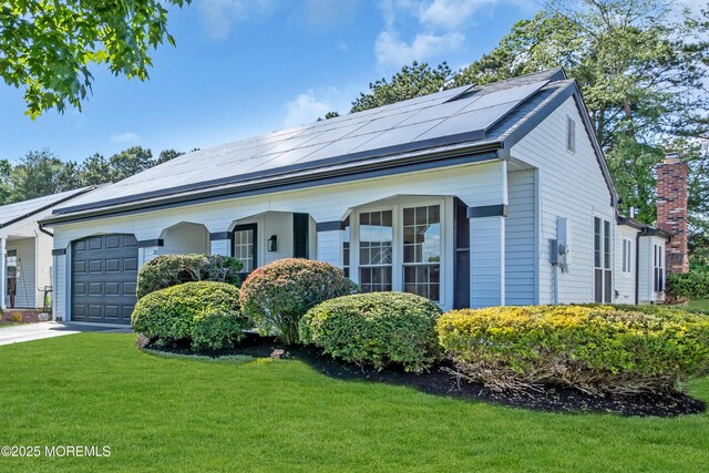 28 Twyford Ln, Manchester, NJ 08759 - view of front of house with a front lawn, roof mounted solar panels, an attached garage, driveway, and a chimney