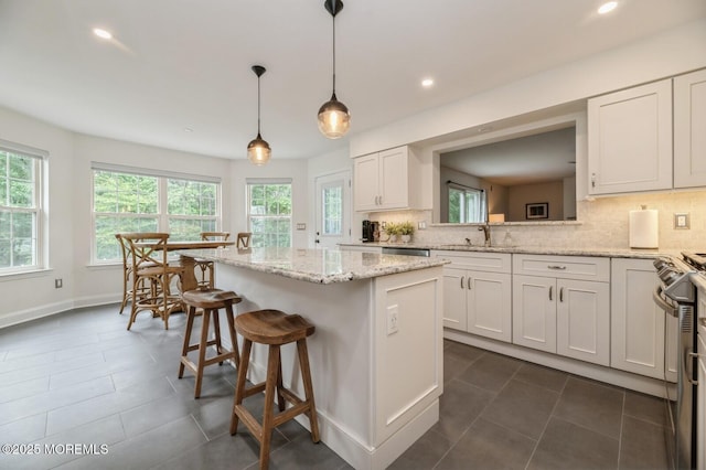 30 Thousand Oaks Ter, Howell, NJ 07731 - kitchen featuring a center island, tasteful backsplash, a breakfast bar, white cabinets, and dark tile patterned flooring