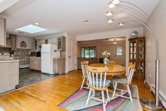 668 Clifton Ave, Toms River, NJ 08753 - dining space with a skylight, baseboard heating, dark wood-type flooring, and a baseboard radiator