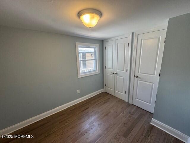13 John St, Hazlet, NJ 07730 - unfurnished bedroom featuring dark wood-style flooring, baseboards, and a closet