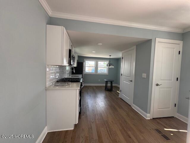 13 John St, Hazlet, NJ 07730 - kitchen featuring stainless steel microwave, white cabinets, light countertops, dark wood-style flooring, and baseboards