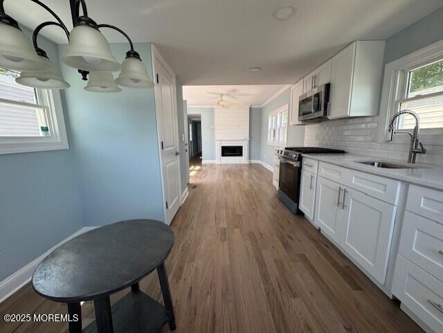 13 John St, Hazlet, NJ 07730 - kitchen featuring appliances with stainless steel finishes, a sink, dark wood-type flooring, white cabinets, and healthy amount of natural light