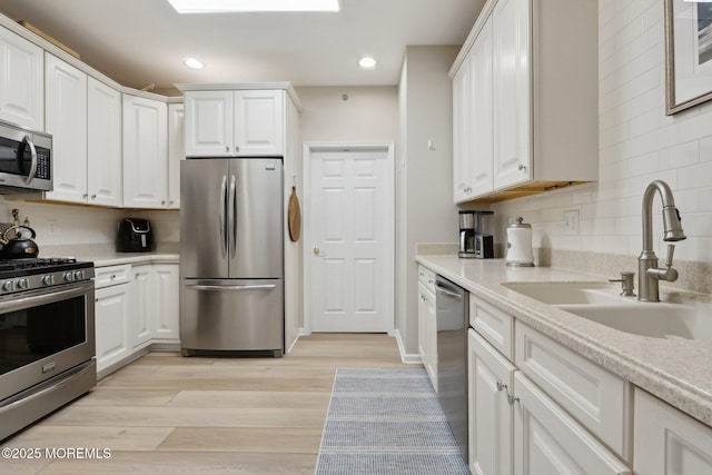33 Cooper Ave Unit 401, Long Branch, NJ 07740 - kitchen featuring appliances with stainless steel finishes, a sink, white cabinets, backsplash, and light countertops
