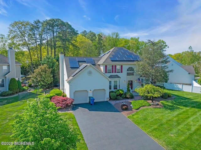 35 Spruce Meadows Dr, Monroe, NJ 08831 - view of front of home with asphalt driveway, roof mounted solar panels, a garage, and a chimney