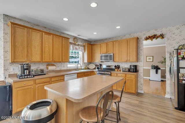 35 Spruce Meadows Dr, Monroe, NJ 08831 - kitchen with appliances with stainless steel finishes, wallpapered walls, a sink, a breakfast bar, and light wood-style flooring