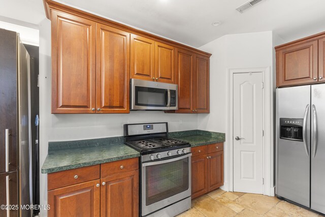 17 Meadow Run Ct, Jackson, NJ 08527 - kitchen featuring stainless steel appliances, dark countertops, stone tile flooring, and brown cabinetry