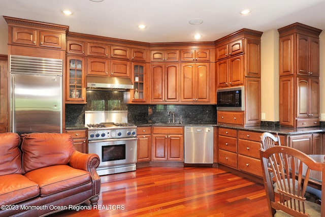 211 Cedar Ave, Long Branch, NJ 07740 - kitchen with built in appliances, under cabinet range hood, a sink, glass insert cabinets, and dark wood finished floors