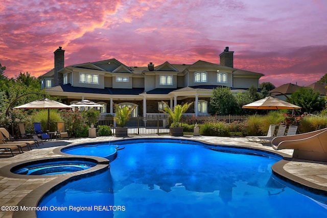 211 Cedar Ave, Long Branch, NJ 07740 - pool at dusk featuring a water slide, a patio area, and a pool with connected hot tub