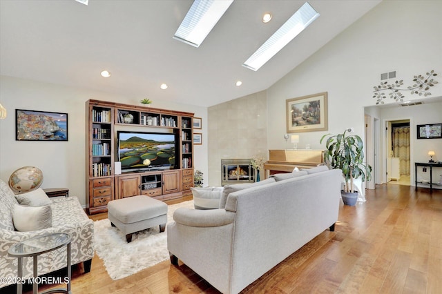56 Hazel Dr, Freehold, NJ 07728 - living area featuring high vaulted ceiling, light wood-style floors, a tiled fireplace, recessed lighting, and a skylight