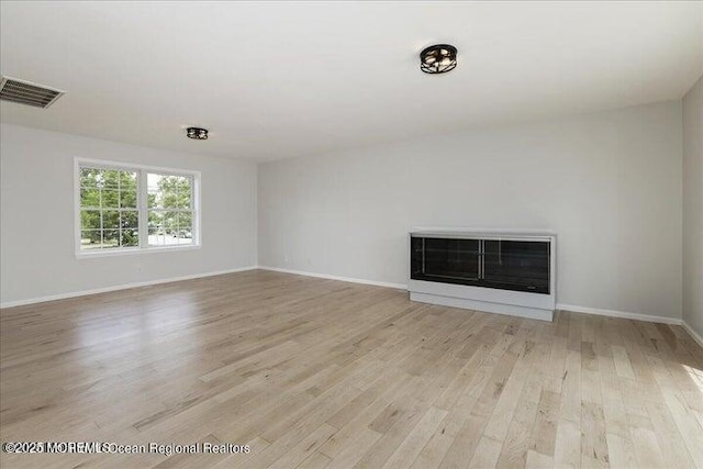 110 Island Rd, Toms River, NJ 08753 - unfurnished living room featuring a glass covered fireplace, light wood-type flooring, and baseboards