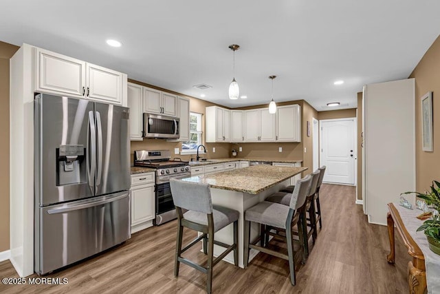 119 Darien Rd, Howell, NJ 07731 - kitchen with appliances with stainless steel finishes, light wood-style flooring, light stone counters, a breakfast bar, and white cabinets