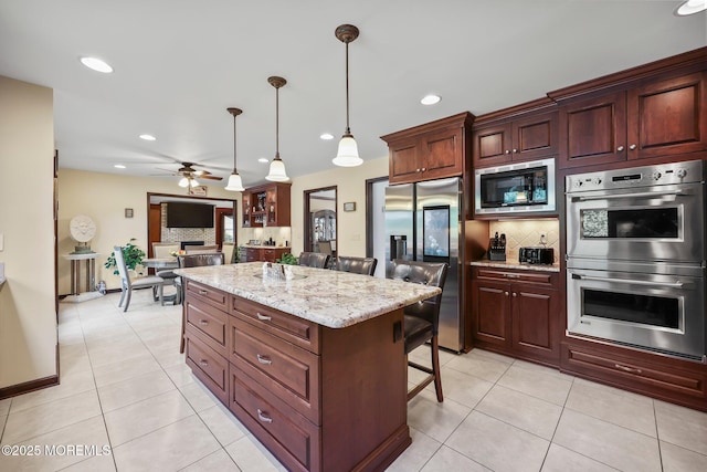 21 Windswept Ln, Freehold, NJ 07728 - kitchen featuring appliances with stainless steel finishes, a ceiling fan, decorative backsplash, a breakfast bar area, and light tile patterned flooring