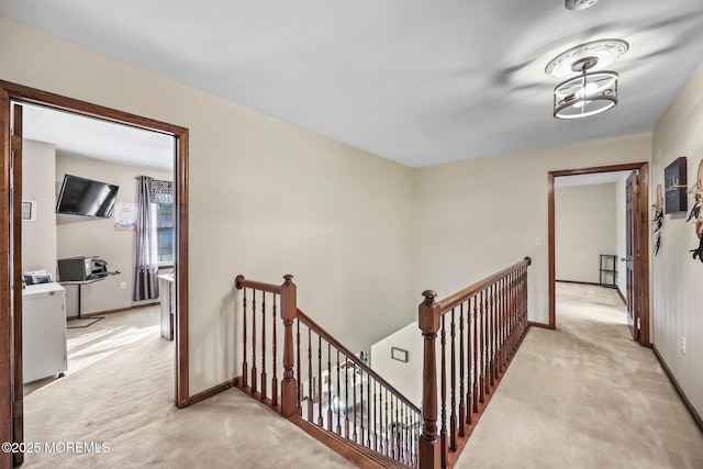 21 Windswept Ln, Freehold, NJ 07728 - hall with an upstairs landing, light colored carpet, washer / clothes dryer, and baseboards