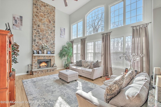11 Elkridge Way, Manalapan, NJ 07726 - living room featuring a towering ceiling, ceiling fan, a stone fireplace, light wood-type flooring, and baseboards