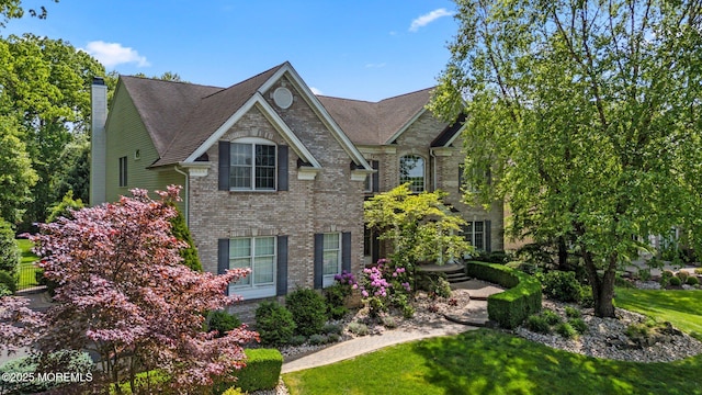11 Elkridge Way, Manalapan, NJ 07726 - view of front facade with brick siding, a chimney, and a front yard