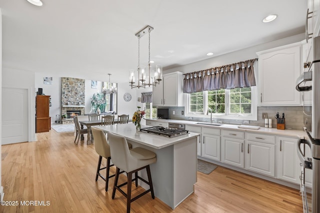 11 Elkridge Way, Manalapan, NJ 07726 - kitchen with a sink, stainless steel gas cooktop, decorative backsplash, white cabinets, and a center island