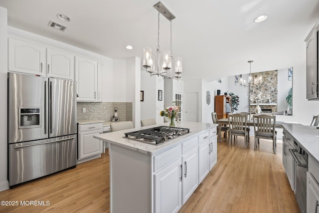 11 Elkridge Way, Manalapan, NJ 07726 - kitchen featuring appliances with stainless steel finishes, a chandelier, tasteful backsplash, light wood-style floors, and decorative light fixtures