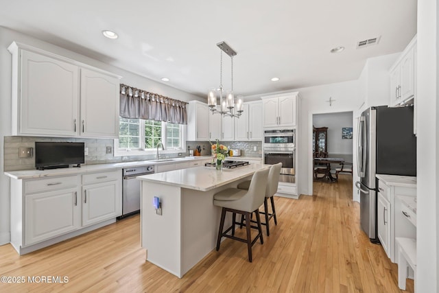 11 Elkridge Way, Manalapan, NJ 07726 - kitchen with stainless steel appliances, white cabinetry, tasteful backsplash, a chandelier, and a breakfast bar area