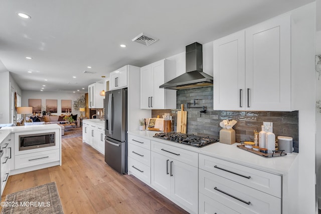 2574 Algonkin Trl, Manasquan, NJ 08736 - kitchen with wall chimney exhaust hood, stainless steel refrigerator with ice dispenser, built in microwave, black gas stovetop, and open floor plan