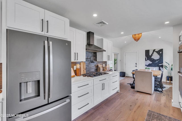2574 Algonkin Trl, Manasquan, NJ 08736 - kitchen featuring stainless steel fridge with ice dispenser, wall chimney range hood, gas stovetop, white cabinets, and lofted ceiling