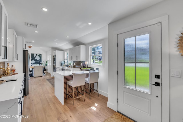 2574 Algonkin Trl, Manasquan, NJ 08736 - kitchen with appliances with stainless steel finishes, white cabinetry, a breakfast bar, a peninsula, and backsplash