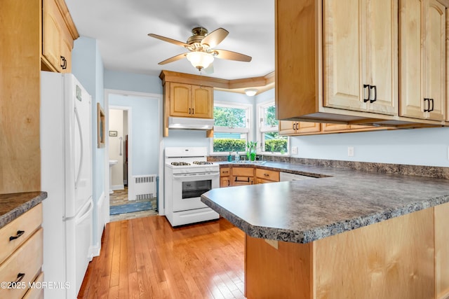 604 N Blvd, Lake Como, NJ 07719 - kitchen featuring white appliances, under cabinet range hood, radiator heating unit, dark countertops, and light brown cabinetry