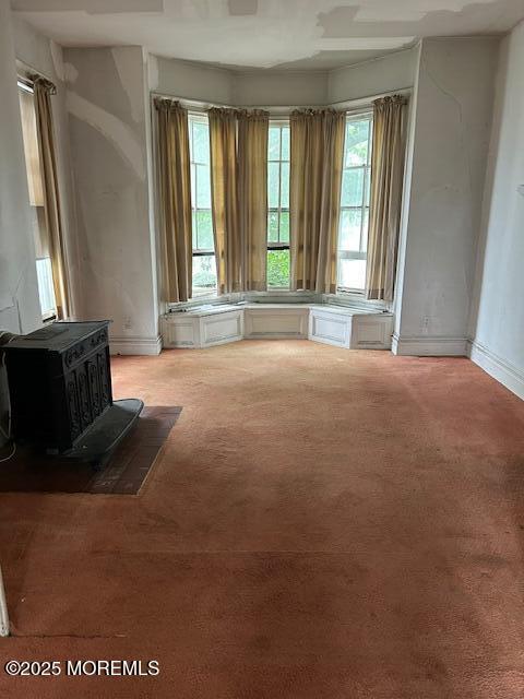 62 Washington St, Red Bank, NJ 07701 - unfurnished living room featuring a wood stove, carpet flooring, and baseboards