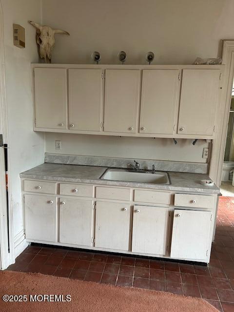 62 Washington St, Red Bank, NJ 07701 - kitchen with a sink, light countertops, white cabinets, and dark tile patterned flooring