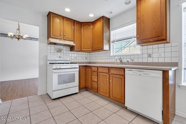 3167 Wood Spring Ln, Toms River, NJ 08755 - kitchen featuring white appliances, under cabinet range hood, brown cabinets, a chandelier, and light countertops