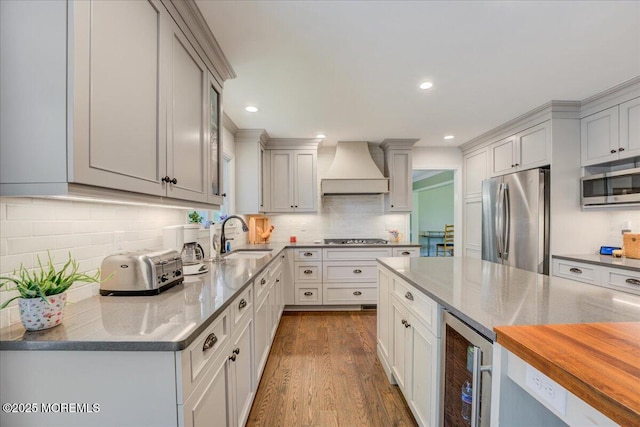 18 Vaughn Dr, Middletown, NJ 07748 - kitchen featuring appliances with stainless steel finishes, custom exhaust hood, a sink, wine cooler, and dark wood-style flooring