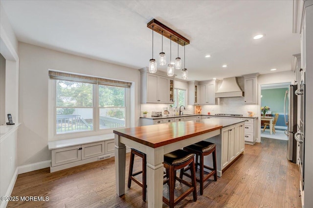 18 Vaughn Dr, Middletown, NJ 07748 - kitchen with butcher block counters, premium range hood, wood finished floors, a sink, and a kitchen breakfast bar