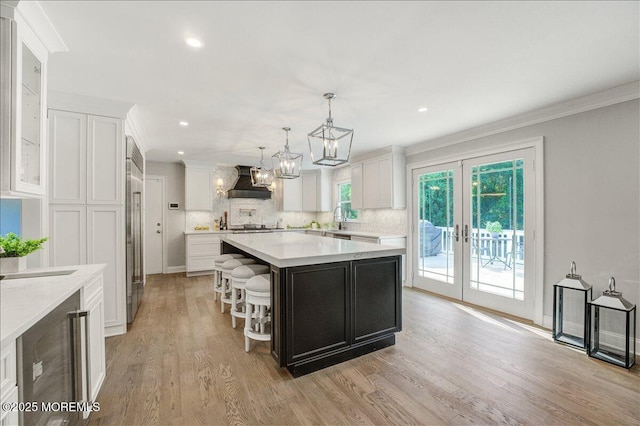 21 Northwoods Rd, Ocean Twp, NJ 07712 - kitchen featuring wall chimney range hood, light countertops, white cabinets, light wood-type flooring, and a center island