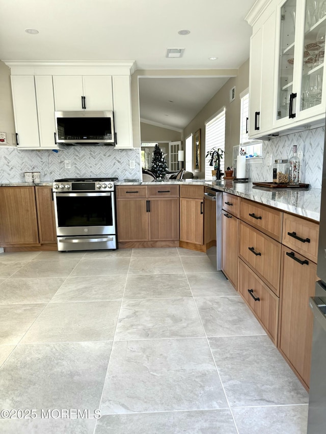 2560 Haverhill Ct, Toms River, NJ 08755 - kitchen featuring appliances with stainless steel finishes, decorative backsplash, light stone countertops, vaulted ceiling, and glass insert cabinets