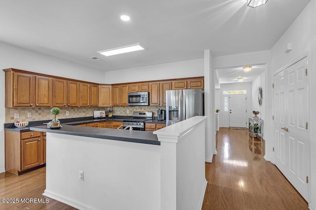 27 Cromwell Ln, Jackson, NJ 08527 - kitchen with stainless steel appliances, dark countertops, an island with sink, brown cabinetry, and tasteful backsplash