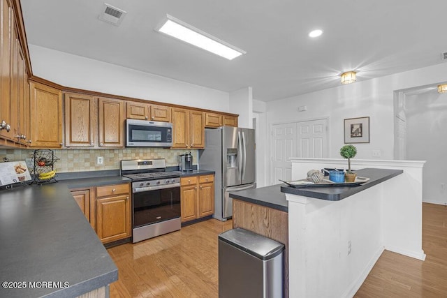 27 Cromwell Ln, Jackson, NJ 08527 - kitchen with appliances with stainless steel finishes, dark countertops, backsplash, and light wood-type flooring